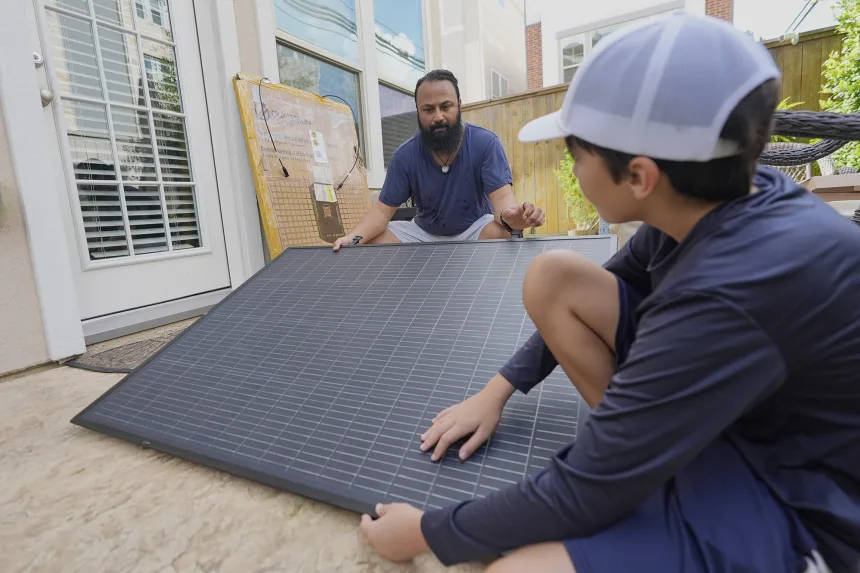 Bhavin Misra and his son Rumi, 10, attach a solar panel while assembling a Craftstrom Solar plug-in kit at their home in Houston, August 2025.